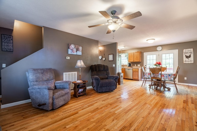 living area with light wood finished floors, baseboards, visible vents, and ceiling fan