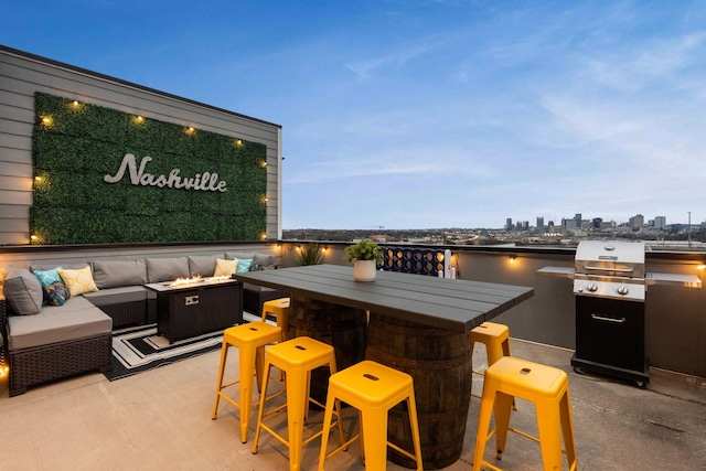 view of patio / terrace with a view of city, exterior kitchen, an outdoor living space with a fire pit, and a water view