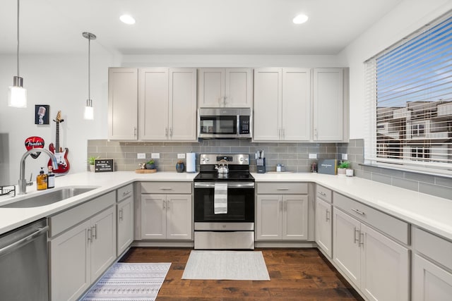 kitchen featuring plenty of natural light, tasteful backsplash, dark wood-type flooring, appliances with stainless steel finishes, and a sink