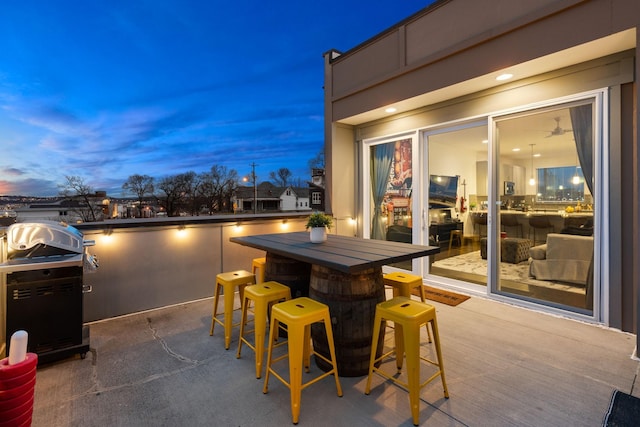 patio terrace at dusk featuring a grill and outdoor dry bar