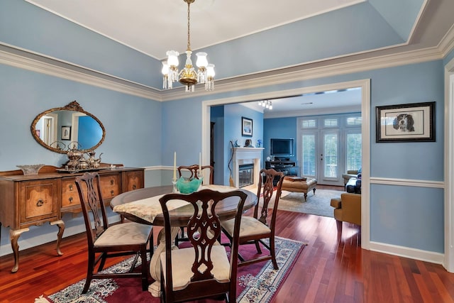 dining room with dark wood-type flooring, a notable chandelier, and crown molding