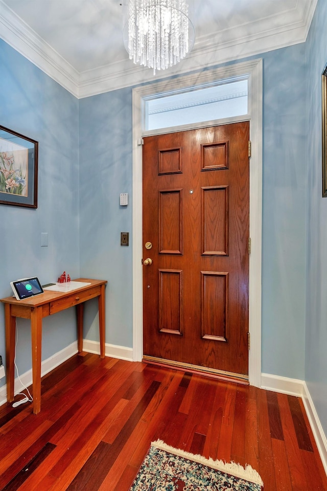 entrance foyer with baseboards, a notable chandelier, wood finished floors, and ornamental molding
