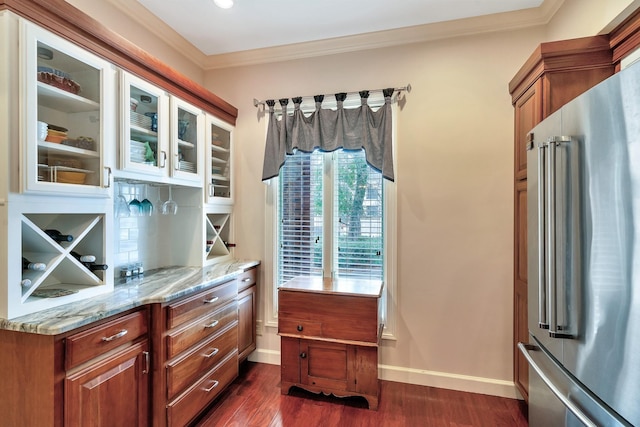 kitchen with dark wood-style flooring, ornamental molding, high end fridge, tasteful backsplash, and light stone counters
