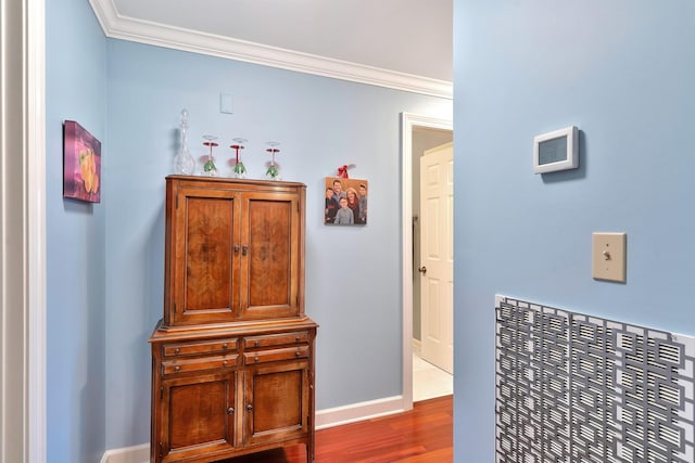 hall featuring baseboards, wood finished floors, and ornamental molding