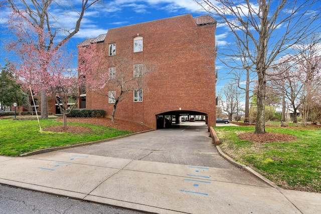 view of side of home featuring driveway and a lawn