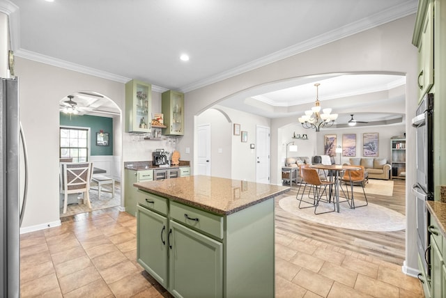 185 Kildeer Dr, Clarksville, TN 37040 - kitchen with a kitchen island, freestanding refrigerator, green cabinets, ceiling fan with notable chandelier, and arched walkways