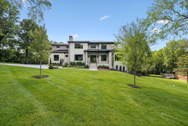 view of front of house with a chimney, a front yard, a standing seam roof, and metal roof