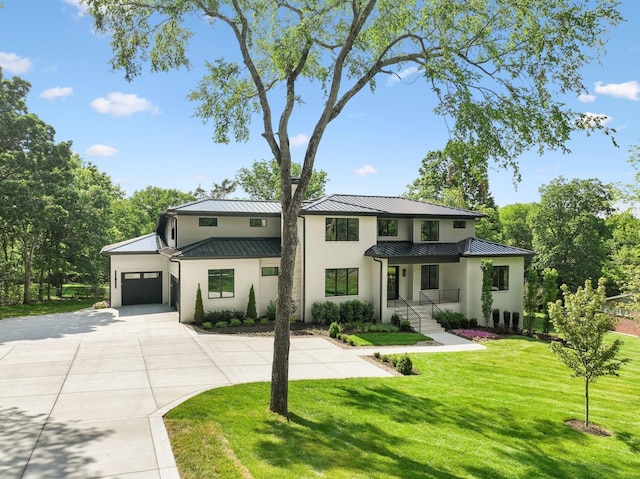 view of front facade featuring concrete driveway, a standing seam roof, an attached garage, metal roof, and a front yard