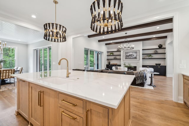 kitchen featuring open floor plan, light wood-style flooring, a sink, and a notable chandelier