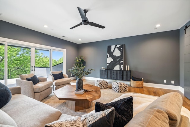 living room with baseboards, ceiling fan, wood finished floors, recessed lighting, and a barn door