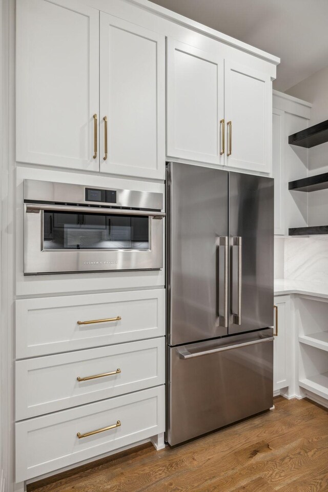 kitchen featuring light countertops, open shelves, white cabinetry, wood finished floors, and stainless steel appliances