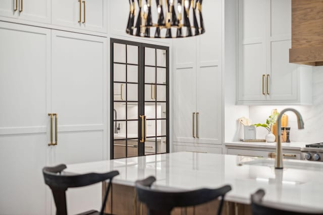 kitchen featuring light countertops, a kitchen bar, french doors, and white cabinets