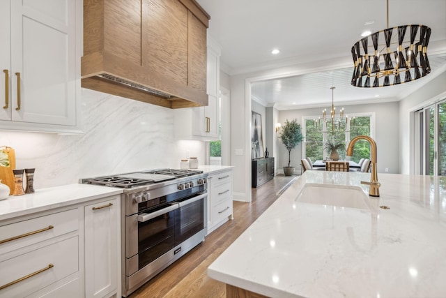 kitchen with crown molding, premium range hood, a sink, range with two ovens, and an inviting chandelier