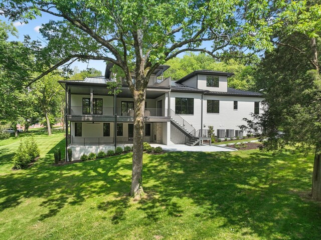 back of property with a lawn, stairs, and a patio area