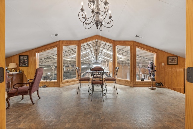 dining area featuring lofted ceiling, visible vents, and wooden walls