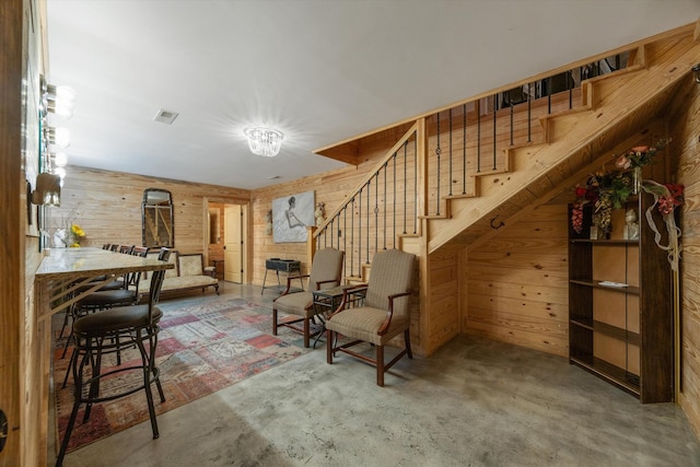 living area featuring visible vents, wooden walls, and stairway