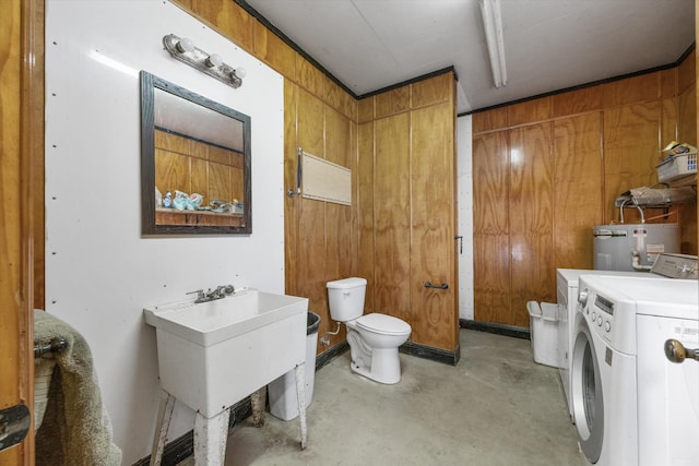 half bath with washing machine and clothes dryer, wood walls, toilet, water heater, and unfinished concrete flooring