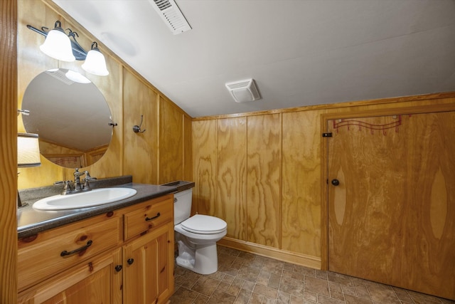 half bath featuring stone finish floor, visible vents, toilet, and vanity