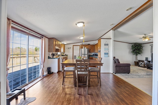 dining room with lofted ceiling, a textured ceiling, wood finished floors, and a ceiling fan