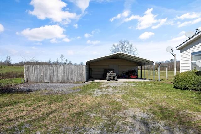 view of yard featuring driveway, a carport, and fence