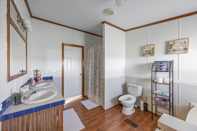 full bath featuring toilet, ornamental molding, a sink, visible vents, and wood finished floors