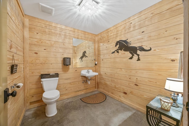 bathroom featuring visible vents, wooden walls, and toilet
