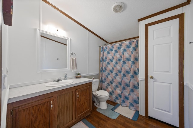 bathroom featuring toilet, vanity, wood finished floors, visible vents, and ornamental molding