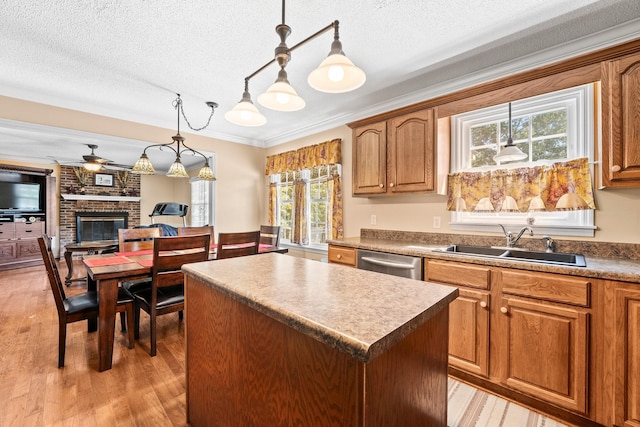 kitchen with a sink, a fireplace, dishwasher, a center island, and light wood-style flooring