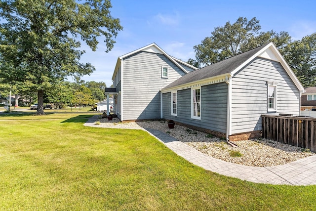 view of side of home featuring a lawn and a shingled roof