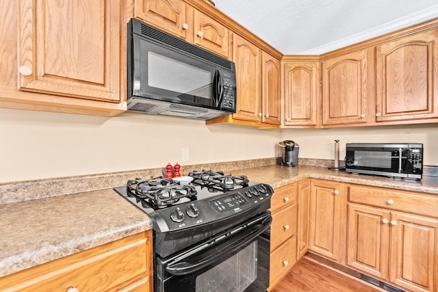 kitchen with light wood-style flooring, black appliances, and light countertops