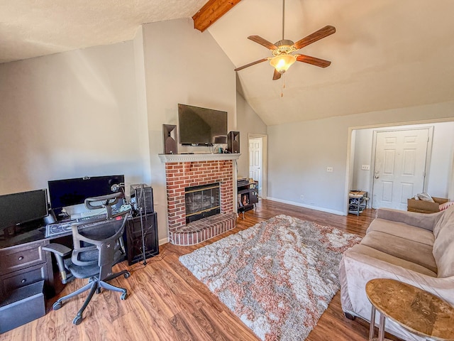 living room with high vaulted ceiling, beamed ceiling, ceiling fan, a fireplace, and wood finished floors