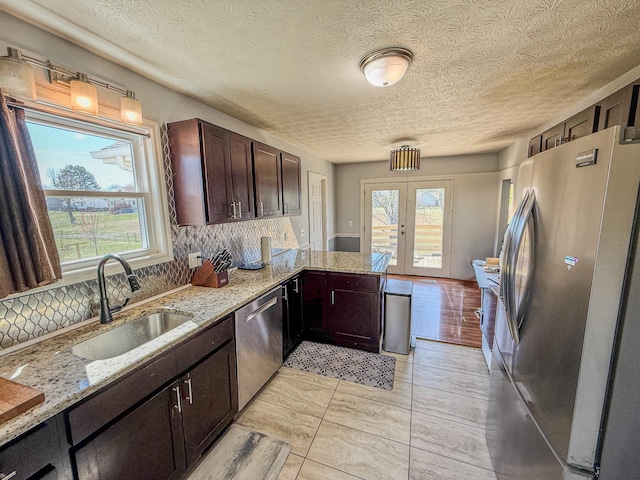 kitchen with a wealth of natural light, french doors, a sink, stainless steel appliances, and decorative backsplash
