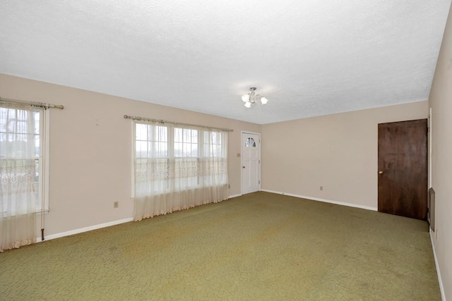 carpeted spare room with baseboards and a textured ceiling
