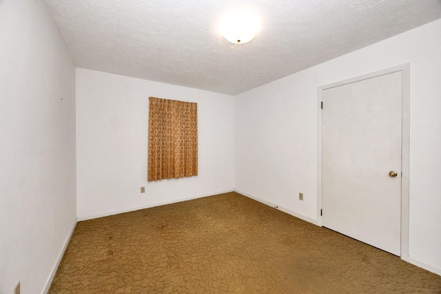 empty room with carpet flooring, baseboards, and a textured ceiling
