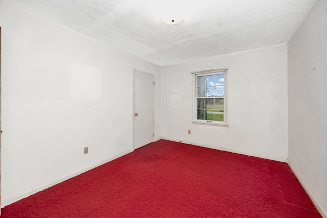 unfurnished room featuring baseboards, dark carpet, and a textured ceiling