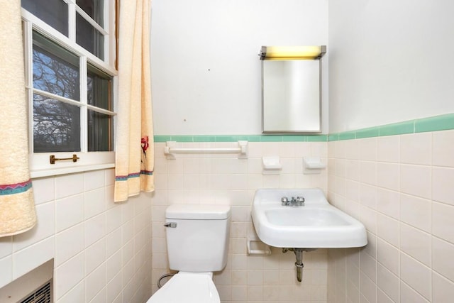 half bathroom with a wainscoted wall, toilet, and a sink