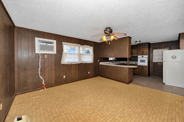 kitchen with light countertops, white appliances, ceiling fan, a peninsula, and a wall mounted air conditioner