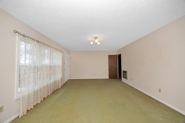 spare room with baseboards, light colored carpet, and a textured ceiling