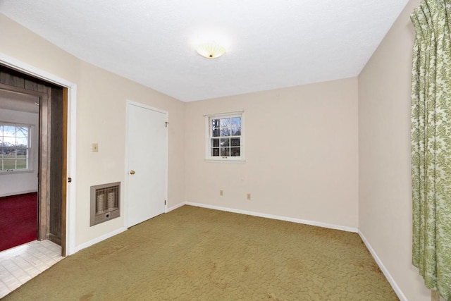 carpeted empty room with heating unit and baseboards