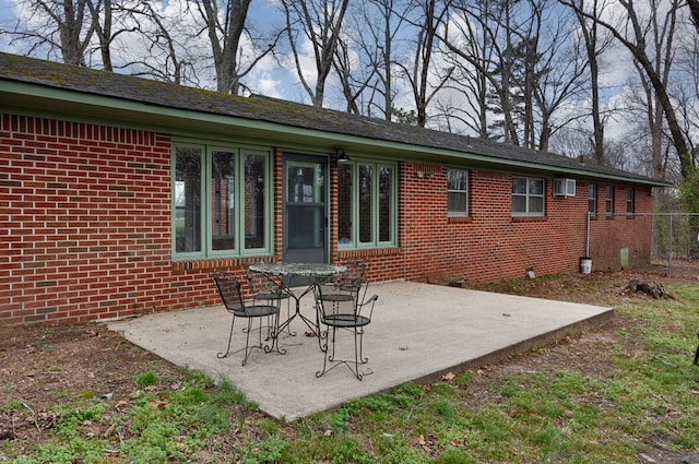 back of property featuring a wall mounted AC, a patio, and brick siding