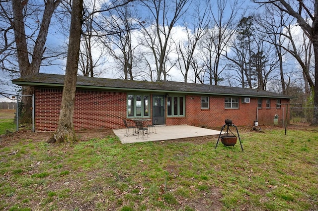rear view of property featuring a patio, fence, brick siding, and a yard
