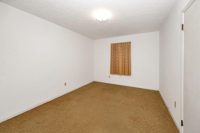 carpeted empty room featuring baseboards and a textured ceiling