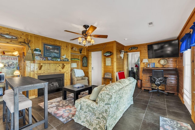 9395 Greenbriar Rd, Waverly, TN 37185 - living room with wooden walls, a glass covered fireplace, a ceiling fan, tile patterned floors, and a desk