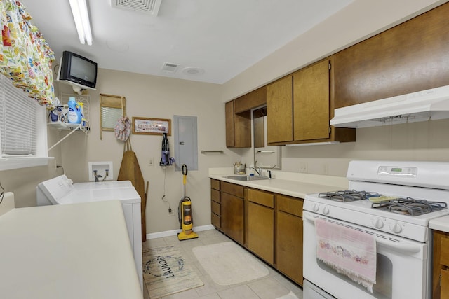 9395 Greenbriar Rd, Waverly, TN 37185 - kitchen with white range with gas stovetop, under cabinet range hood, washing machine and dryer, brown cabinetry, and light countertops