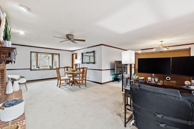 living area with baseboards, ornamental molding, ceiling fan, and light carpet