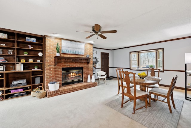 carpeted dining room featuring baseboards, a fireplace, ornamental molding, and a ceiling fan