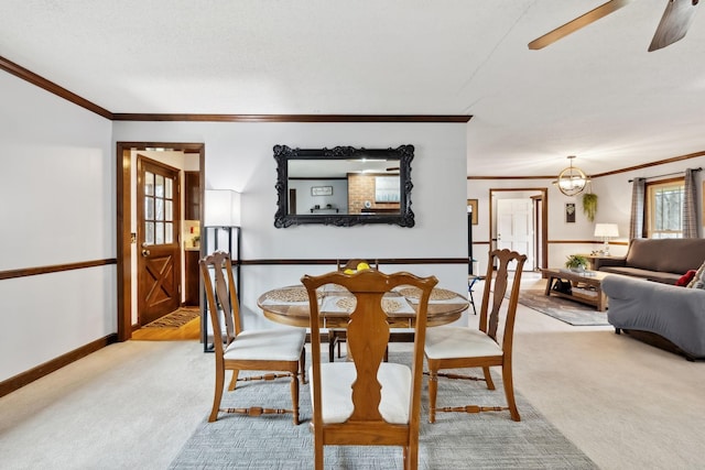 dining area featuring light colored carpet, crown molding, baseboards, and ceiling fan with notable chandelier