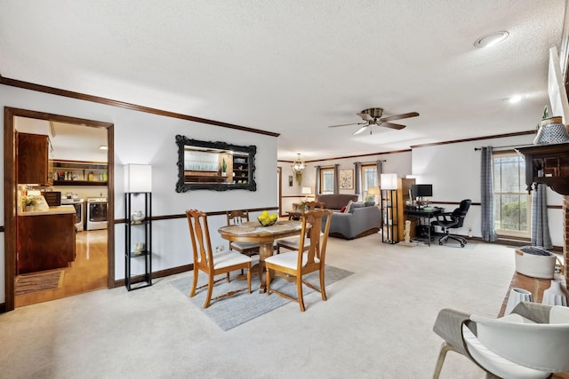dining room featuring crown molding, light colored carpet, a textured ceiling, a ceiling fan, and washing machine and dryer