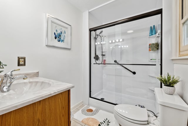 bathroom with toilet, vanity, a stall shower, and tile patterned floors