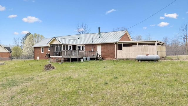rear view of property featuring brick siding, a sunroom, fence, and metal roof